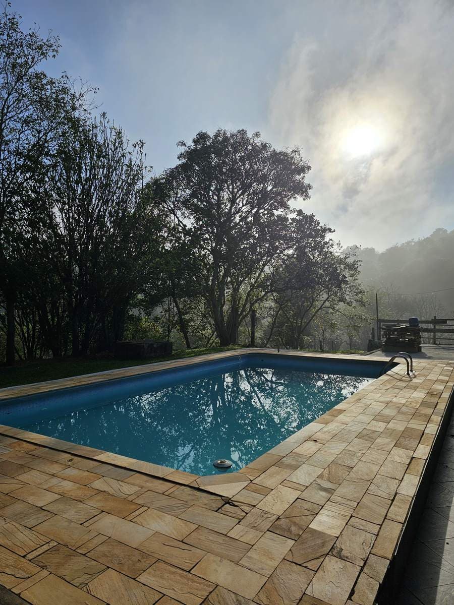 Amanhecer com neblina sobre a piscina e a mata da Pousada Santa Júlia, no km 53 da Rota da Luz, em Santa Branca