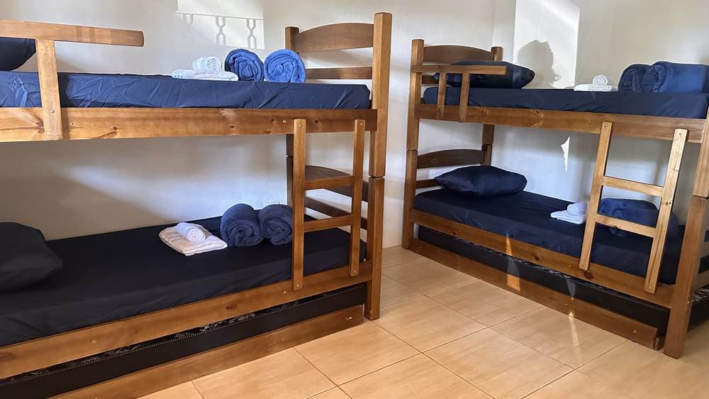 Acomodação preparada com camas, roupas de cama e banheiro privativo na Pousada Santa Júlia
