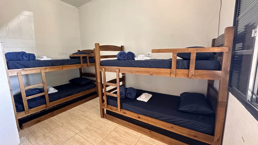 Cama arrumada com roupa de cama completa na Pousada Santa Júlia