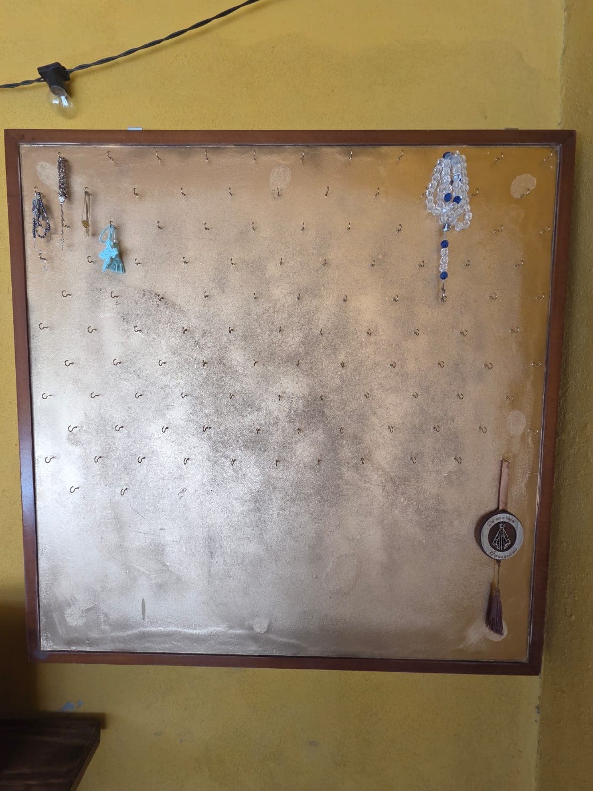 Quadro Terços do Caminho, com ganchos onde os peregrinos penduram seus terços na Pousada Santa Júlia